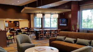 A hotel lobby with a seating area, a bar, and a TV screen. - Fairfield Inn & Suites Springfield Holyoke (Holyoke)