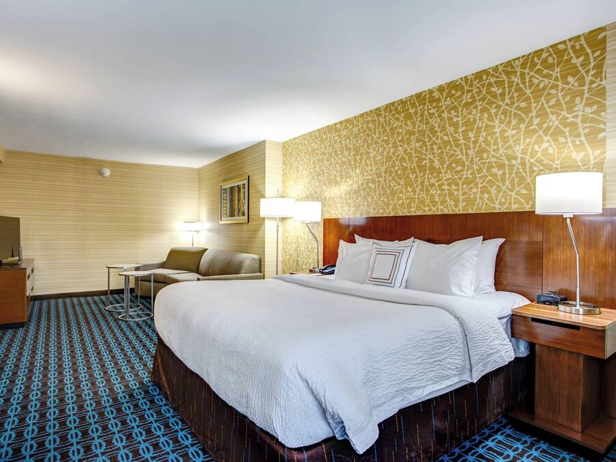 A hotel room with a large bed, bedside tables, a desk, and a chair.