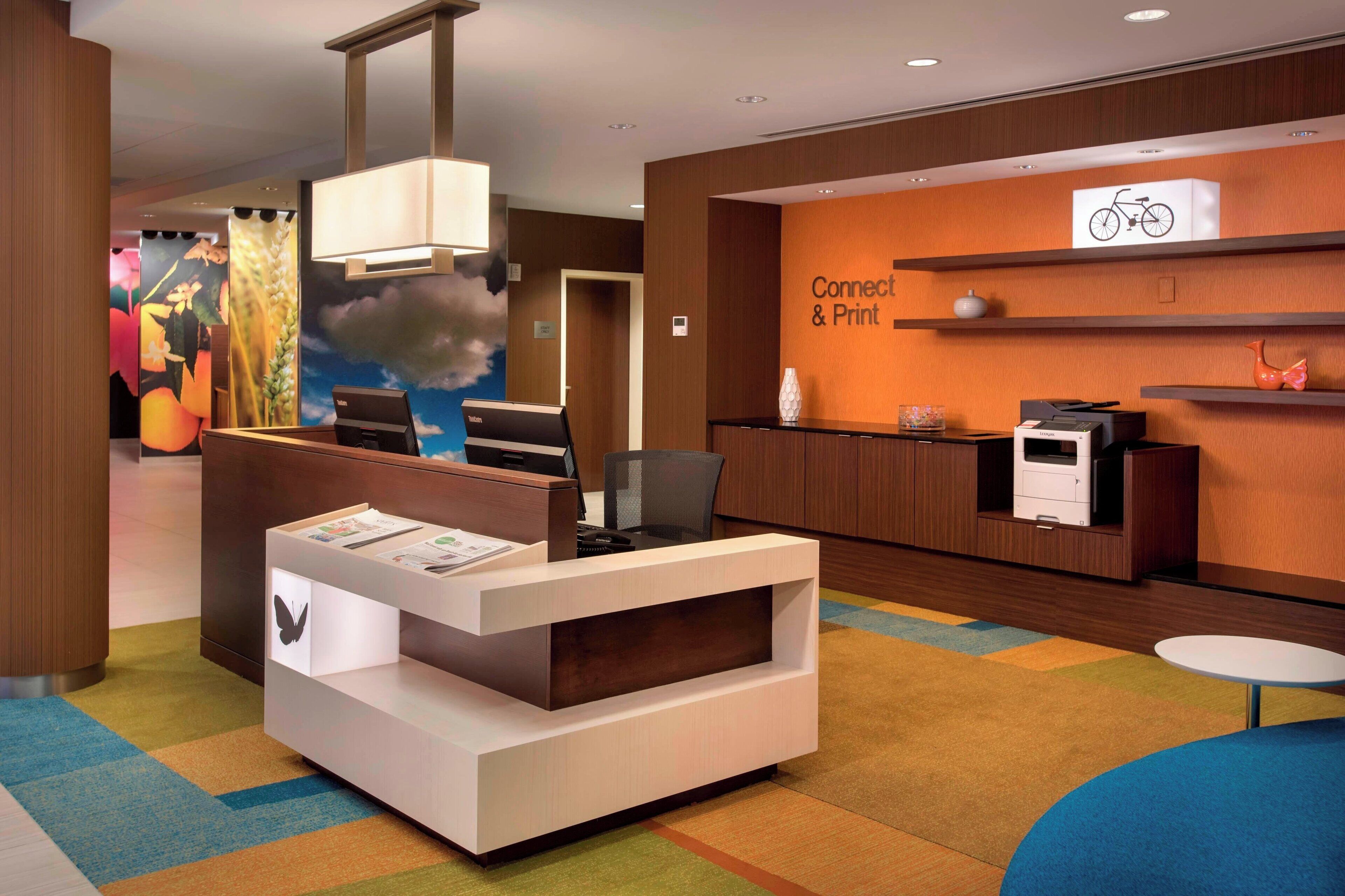 A reception area with a modern desk, a printer, and a wall-mounted sign reading "Connect & Print".