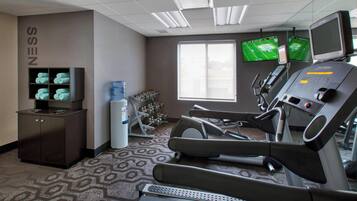 A gym with exercise equipment, a water cooler, and a TV on the wall.