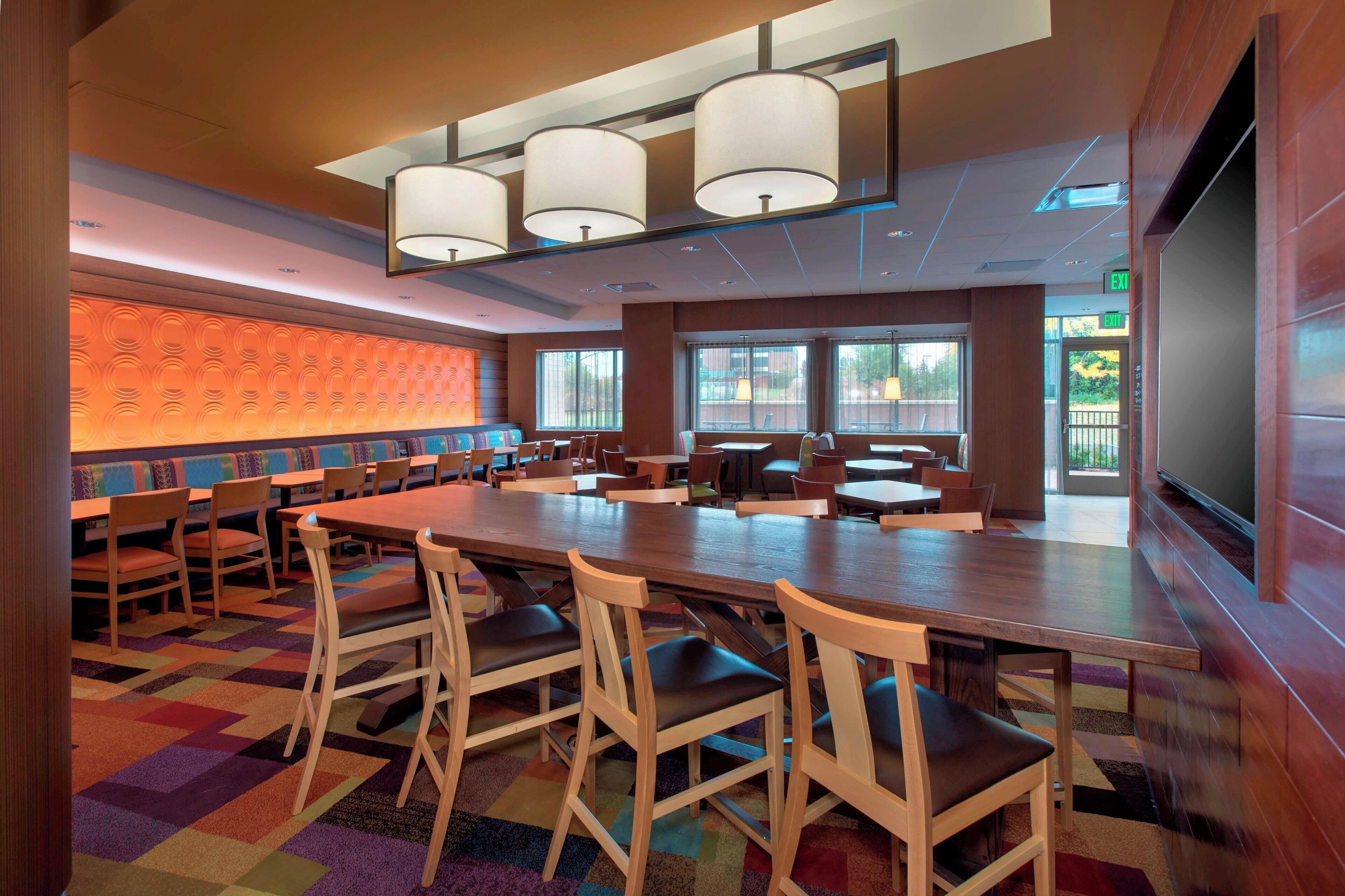 A conference room with a long table, multiple chairs, and a large screen.