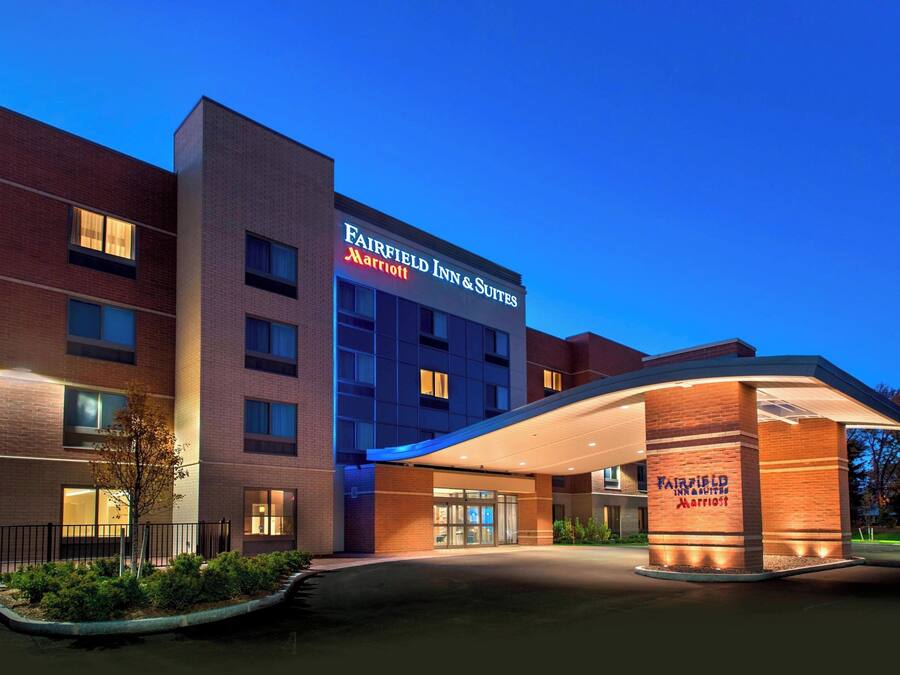 Um hotel Fairfield Inn & Suites com design moderno, apresentando fachada de tijolos e entrada bem iluminada.
