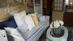 A cozy living room with a sofa, pillows, and a round table with flowers. - The 1720 House (Vineyard Haven)