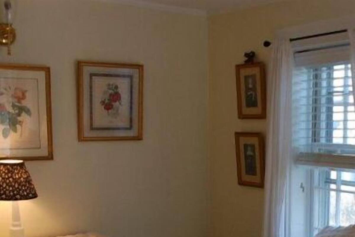 A bedroom with a bed, a nightstand, a lamp, and framed pictures on the wall.