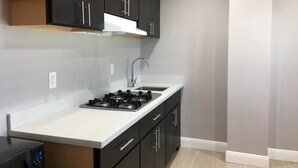 Una cocina moderna con armarios oscuros, encimera blanca y estufa a gas.