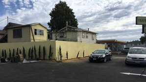 Una casa de dos plantas con garaje, coches aparcados y una señal de calle visible.