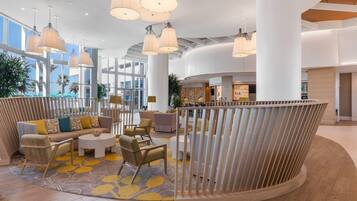 A spacious lobby with a curved seating area, large windows, and hanging pendant lights.