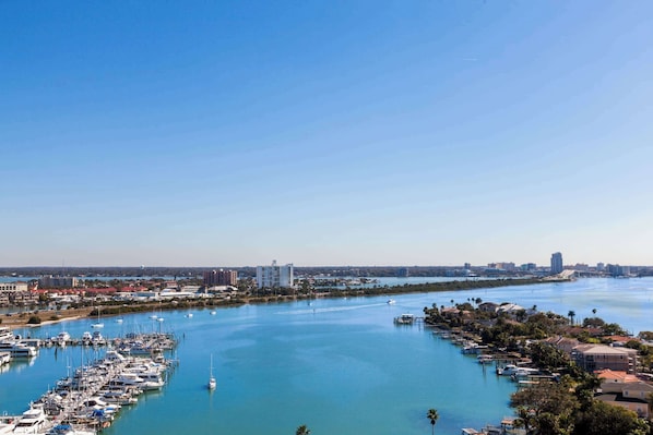 Un puerto deportivo con numerosos barcos amarrados, un cielo azul despejado y un paisaje urbano al fondo.