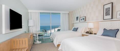 Une chambre d’hôtel avec deux lits, un bureau, une télévision et une vue sur l’océan.