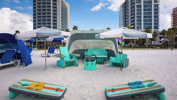 A beachside lounge area with lounge chairs and umbrellas, a pool table, and a small bar area.