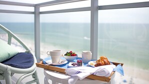 Bandeja de desayuno con comida y bebidas en un balcón con vista al océano.