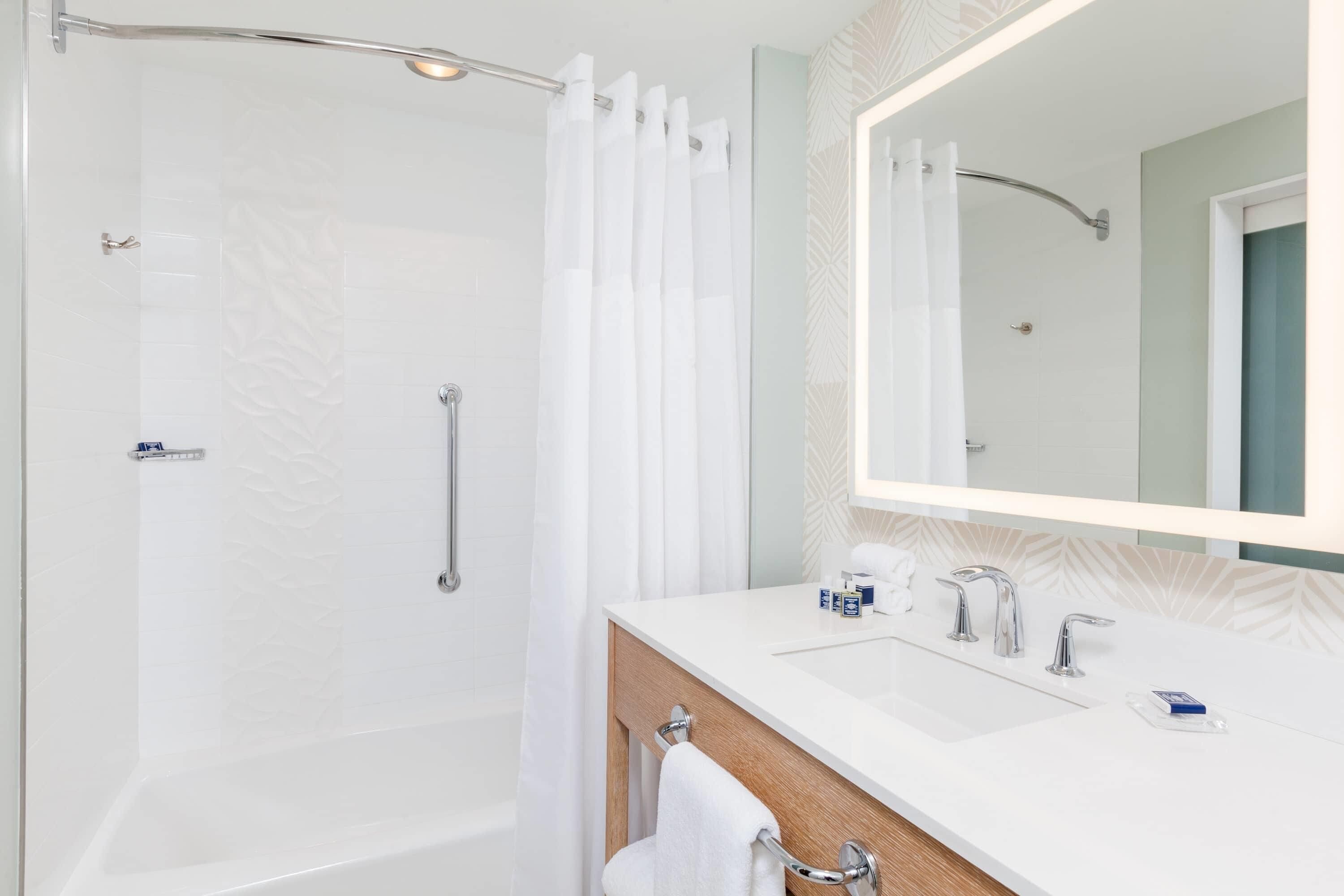 Un baño moderno con ducha, tocador con espejo y bañera.