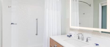 A modern bathroom with a shower, a vanity with a mirror, and a bathtub.