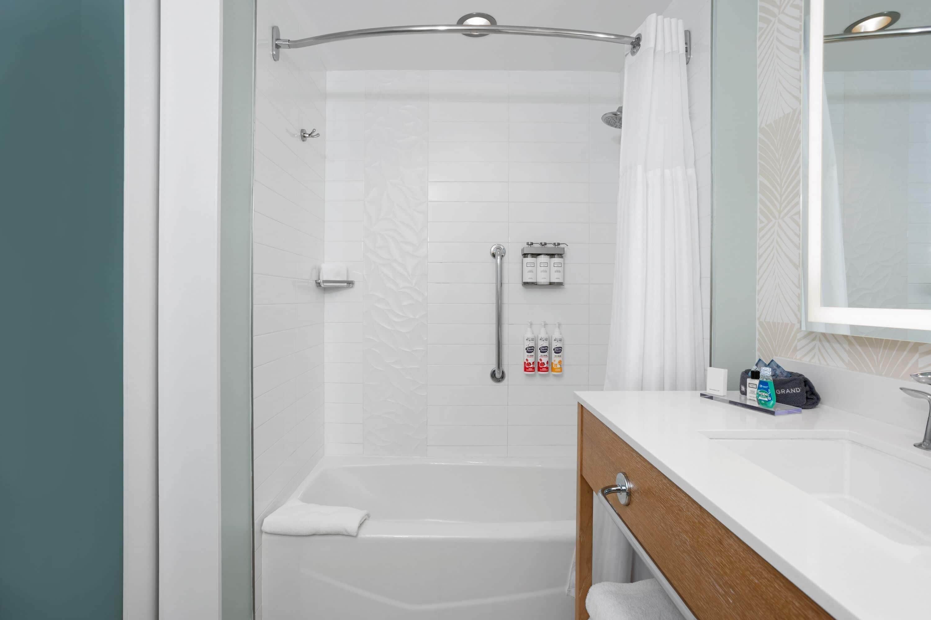 Un baño moderno con cabina de ducha de vidrio, un lavamanos blanco y un mueble de tocador de madera.