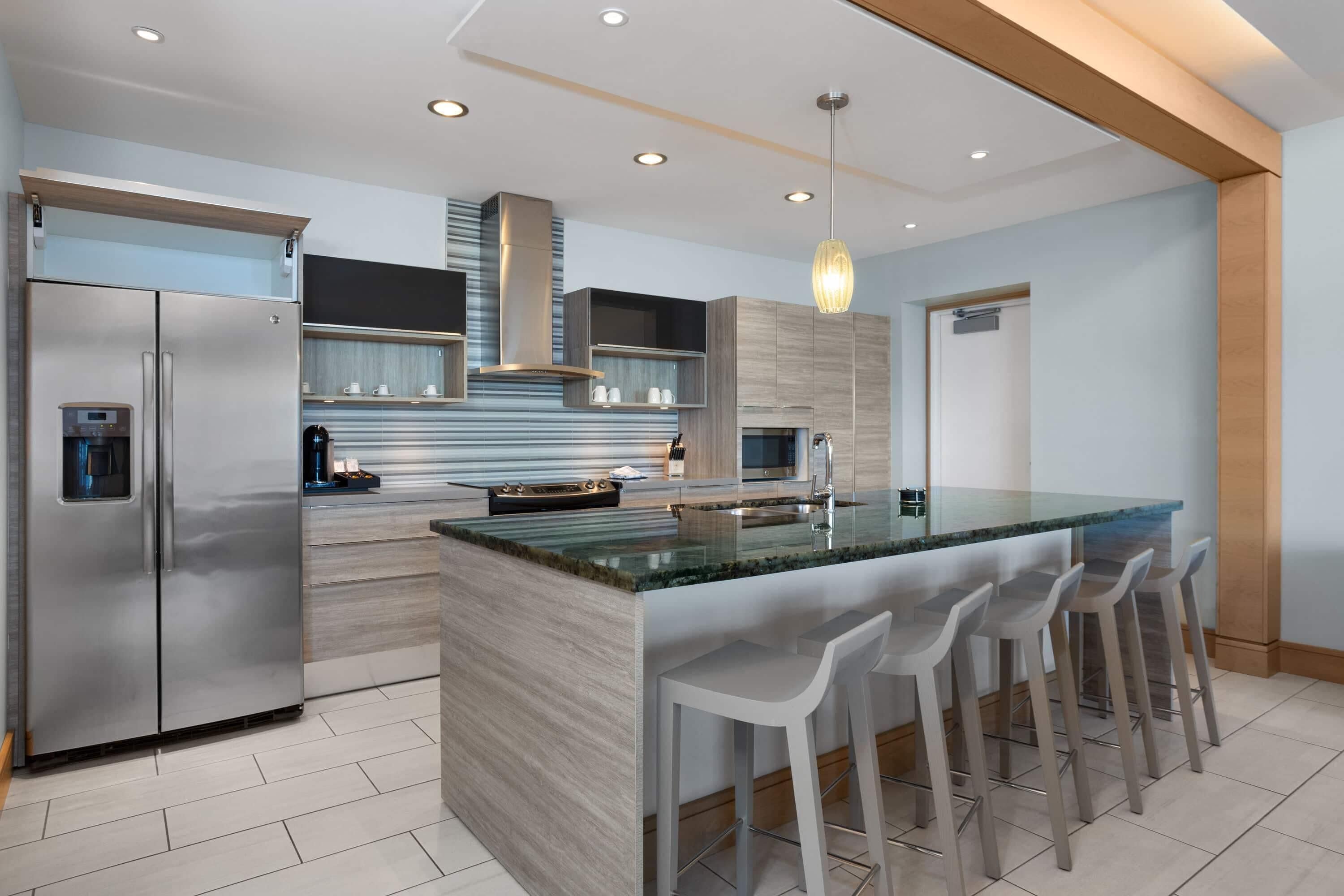 A modern kitchen with a central island, stainless steel appliances, and bar stools.