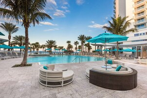 Una piscina al aire libre, sombrillas, sillones reclinables de piscina