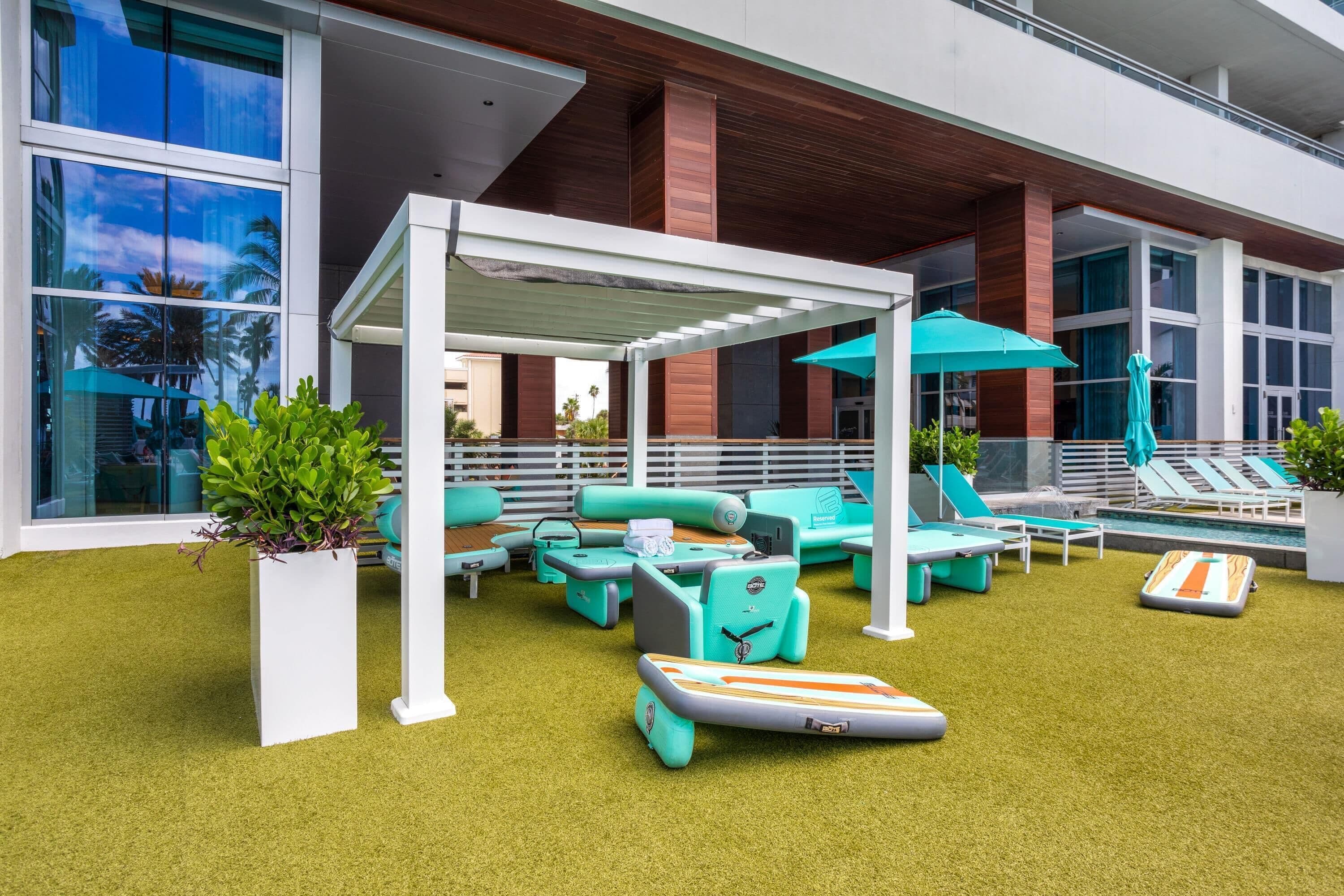 A modern outdoor lounge area with seating, a pool, and a covered patio.