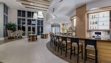 A modern bar area with a curved counter, bar stools, and a display of liquor bottles.