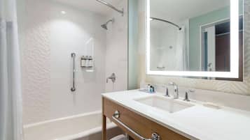 Ein modernes Badezimmer mit Badewanne, Waschtisch inklusive Spiegel und Duschbereich.