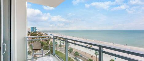A balcony with a view of the beach and ocean.