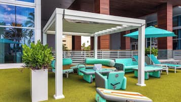 Relax in a shaded outdoor lounge with sofas, lounge chairs, and lush greenery.
