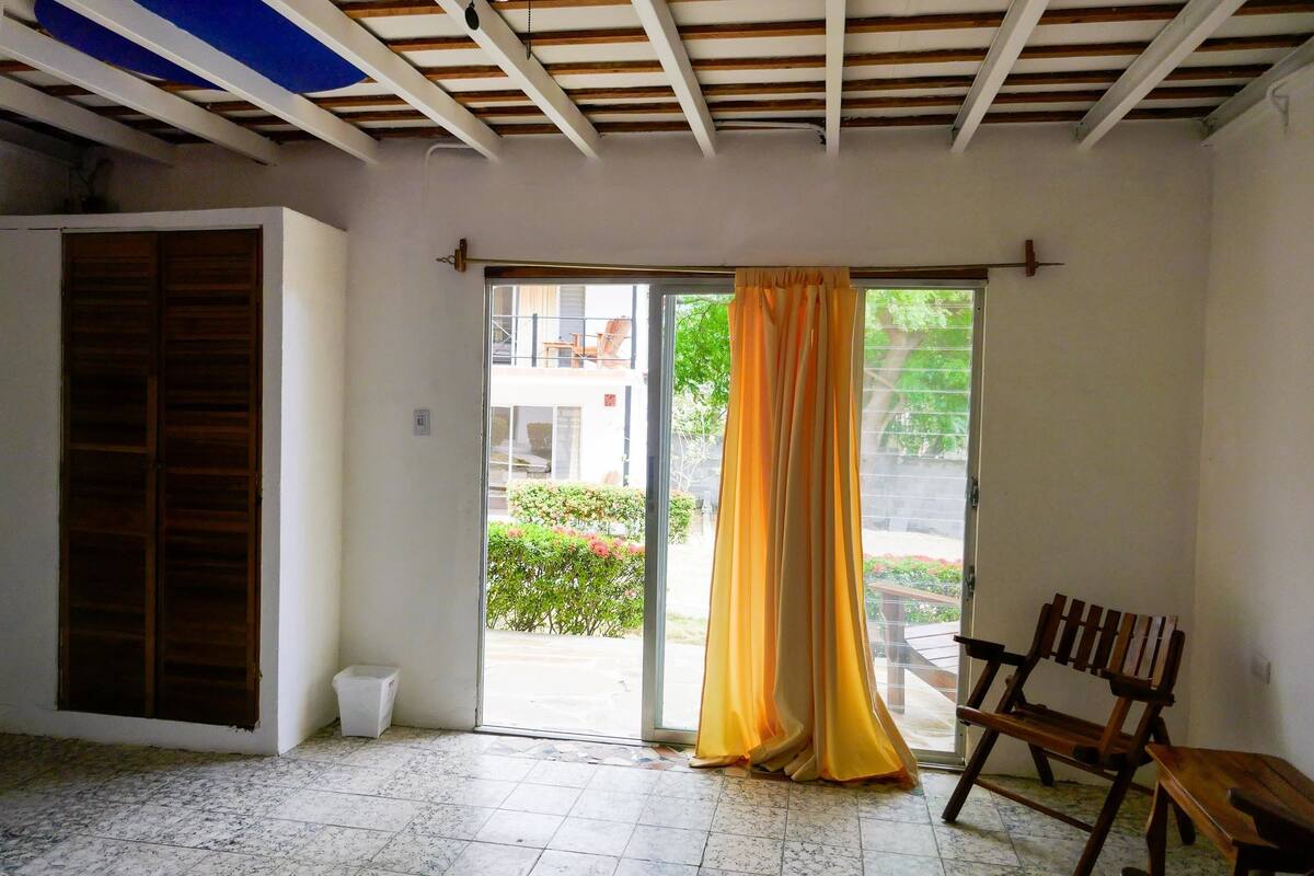 A room with a sliding glass door, a wooden bench, and a small trash bin.