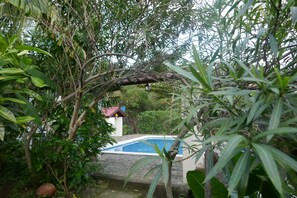 Ein Pool, umgeben von üppiger Vegetation und ein kleines Gebäude mit rotem Dach.