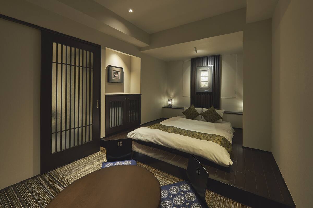 Une chambre de style japonais traditionnel, avec un sol recouvert de tatamis, un lit bas et des portes coulissantes.