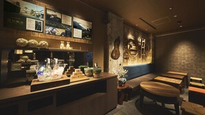 A restaurant with a wooden counter, green ceramic bowls, and a guitar on the wall. - SAKE Kura Hotel Kawasaki Shuku (Kawasaki)