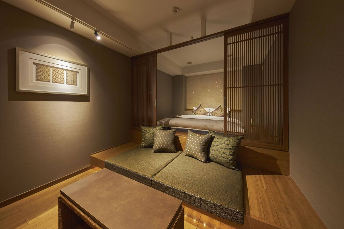 Une pièce de style japonais traditionnel, avec un sol recouvert de tatamis, un lit bas et des paravents coulissants de type shoji.