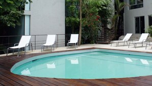 A swimming pool with wooden deck and white lounge chairs.