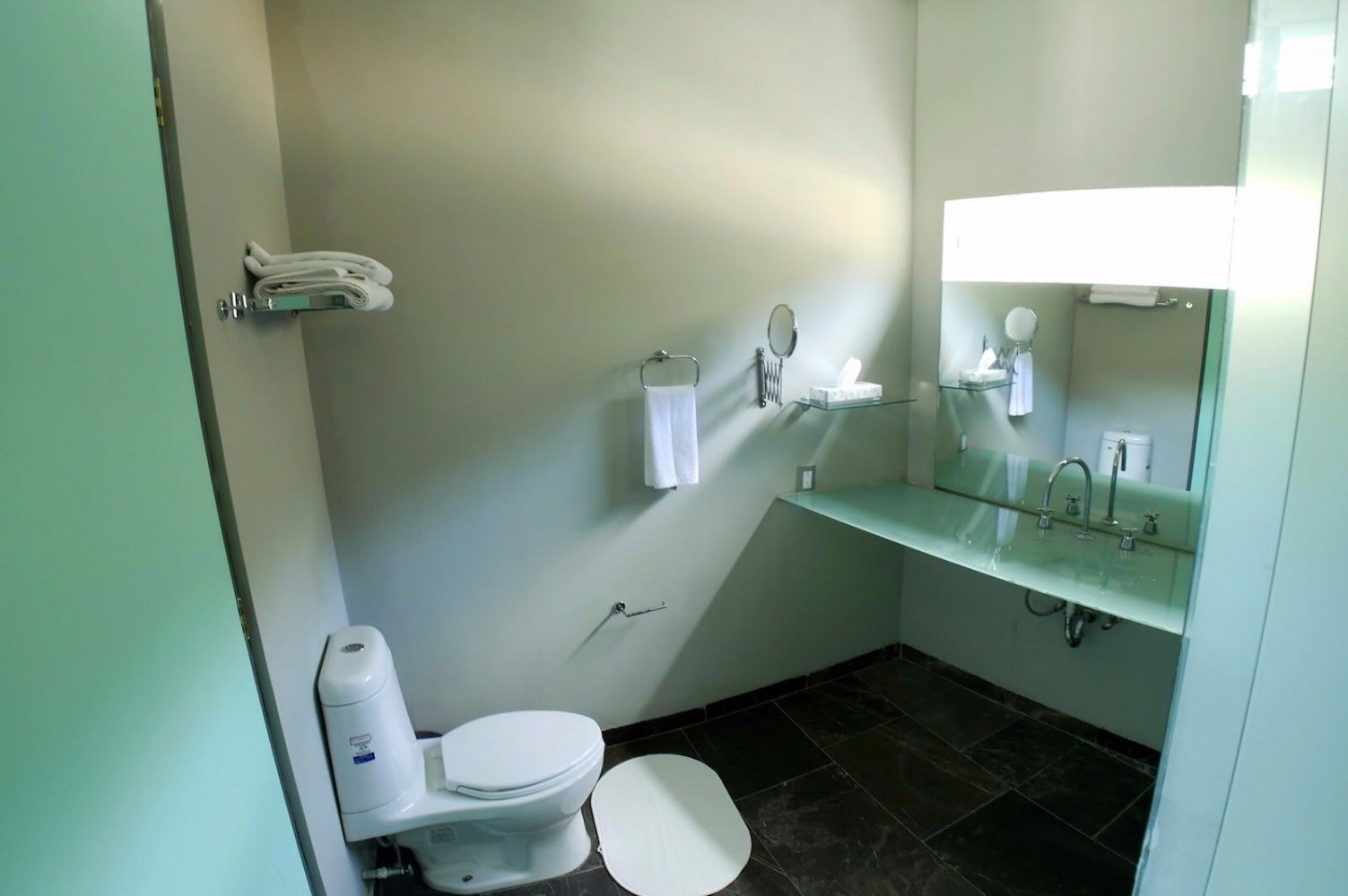 Une petite salle de bain propre, équipée de toilettes, d’un lavabo et d’un miroir.