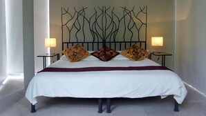 A bed with a white bedspread, two patterned pillows, and a decorative headboard.