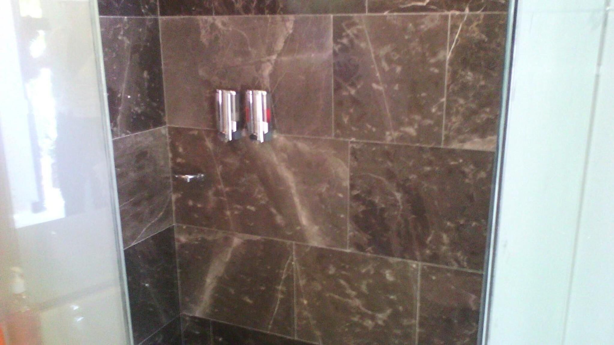 A shower area with dark marble tiles and a glass partition.