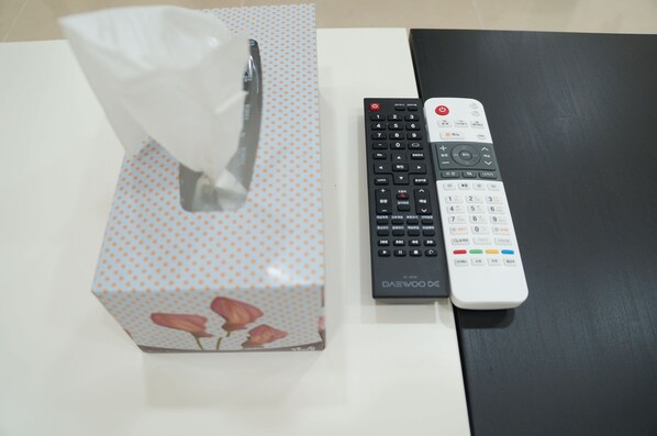 Une boîte de mouchoirs et deux télécommandes sur une table.