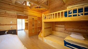 A wooden cabin with bunk beds, a wooden floor, and a staircase leading to a door.