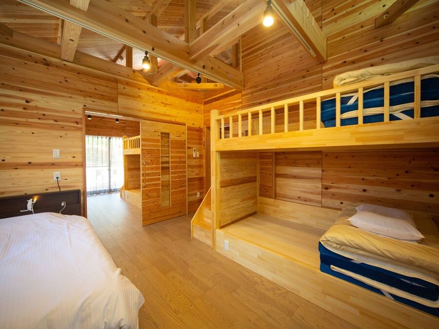 A wooden cabin with bunk beds, a wooden floor, and a staircase leading to a door.