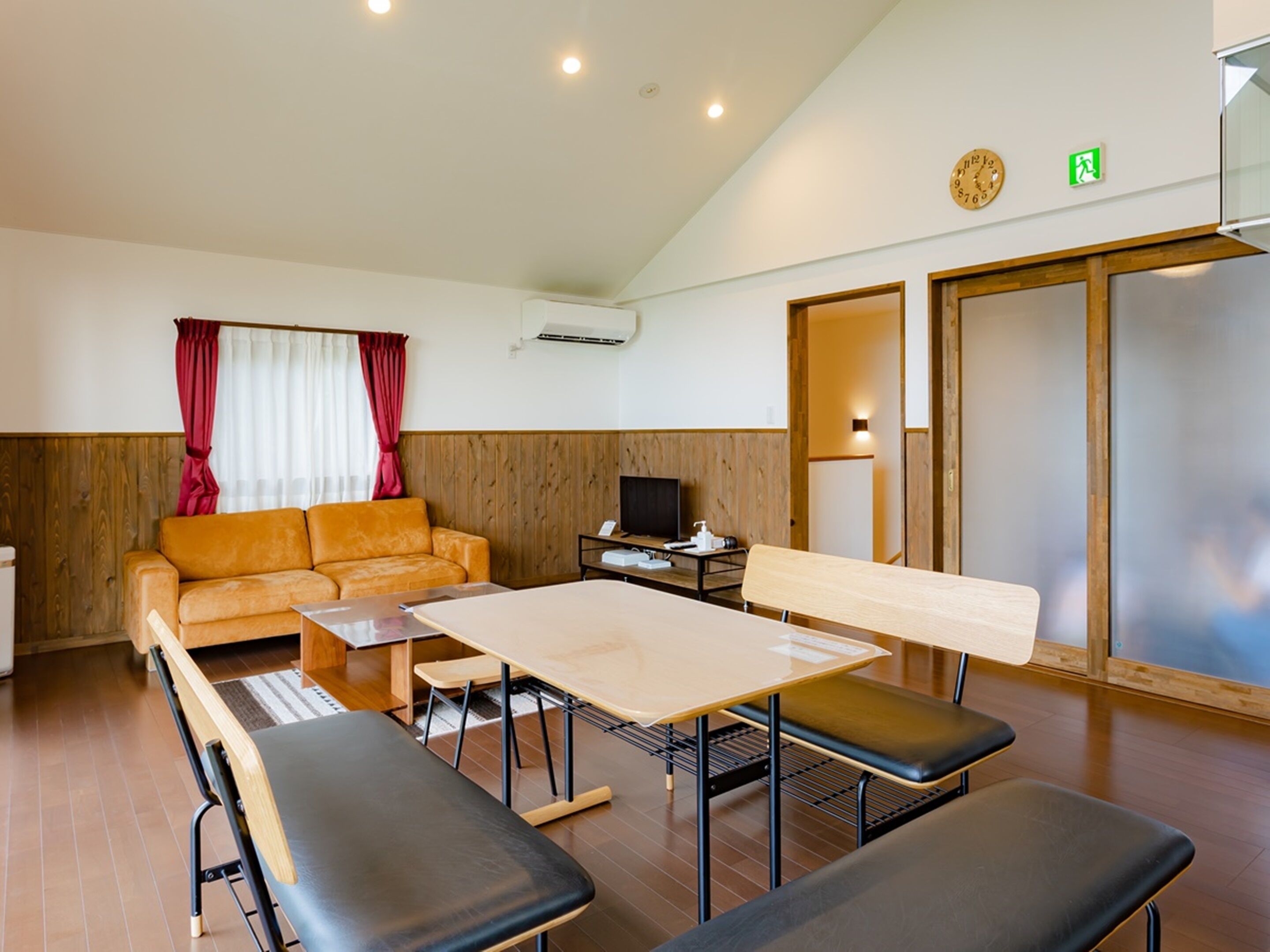 A room with a wooden bench, a sofa, a table, and a television.