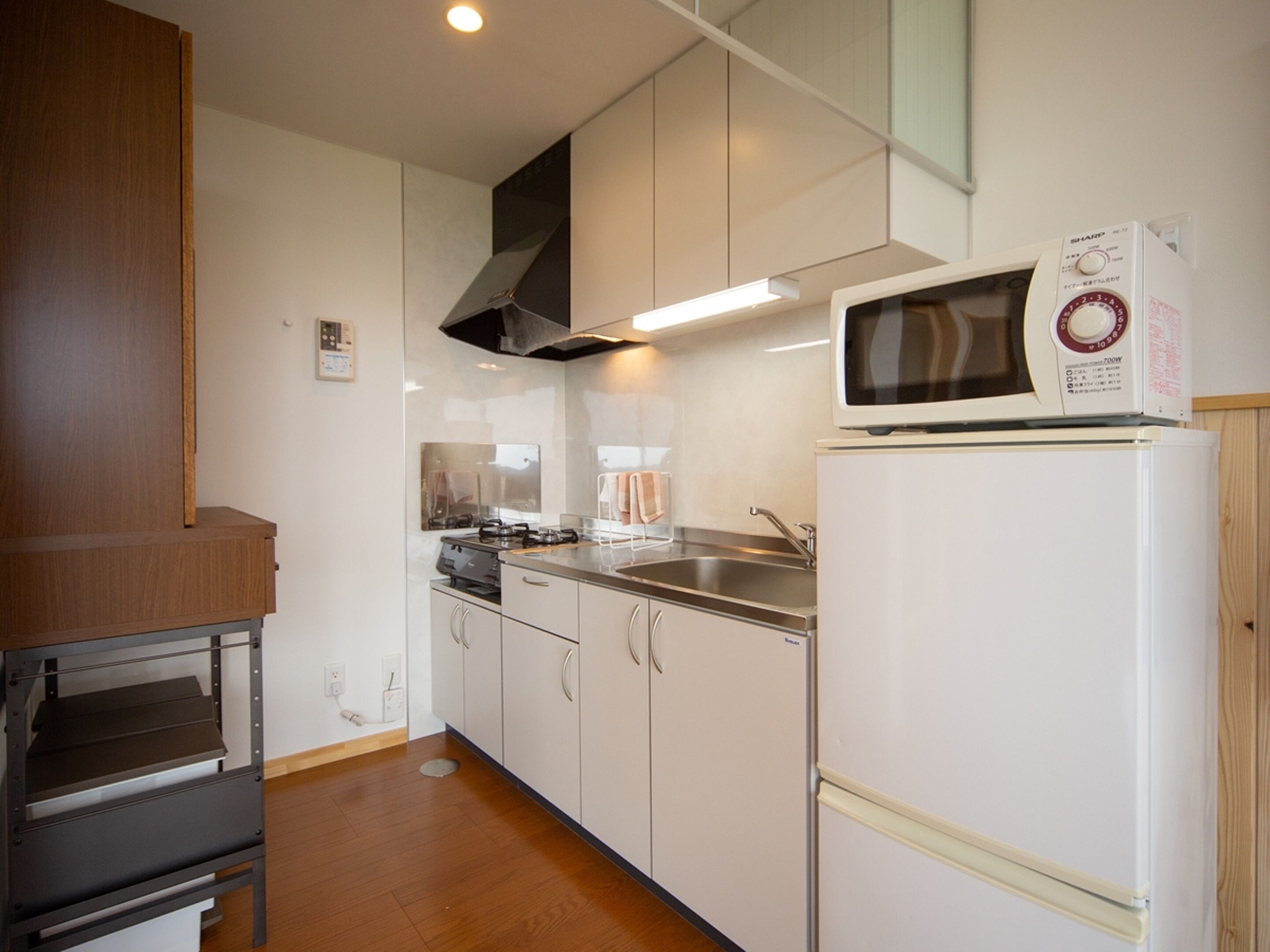 A compact kitchen with white cabinets, a microwave, a stove, and a sink.
