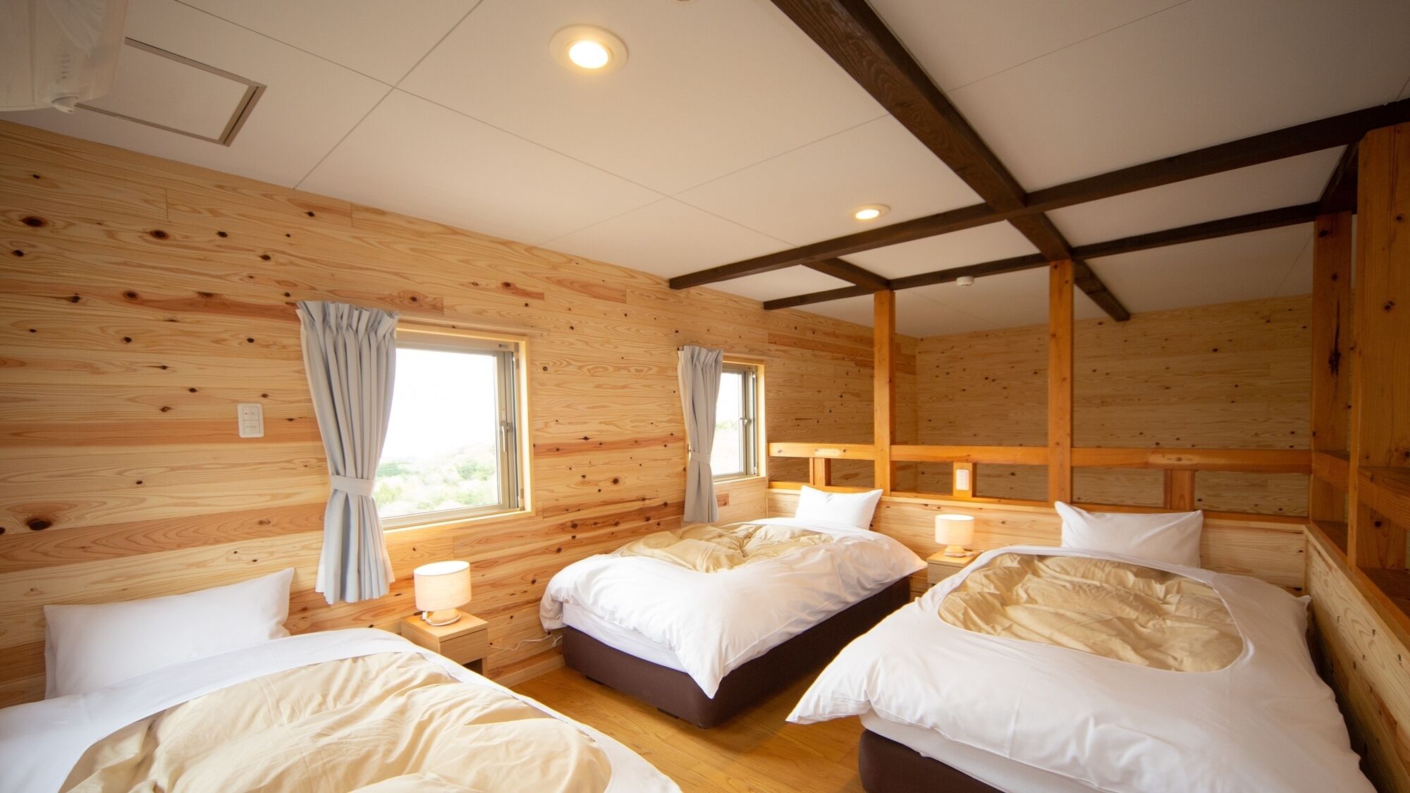 Ein blockhaushaltiger Raum mit drei Betten, Holzwänden und einer schrägen Decke.