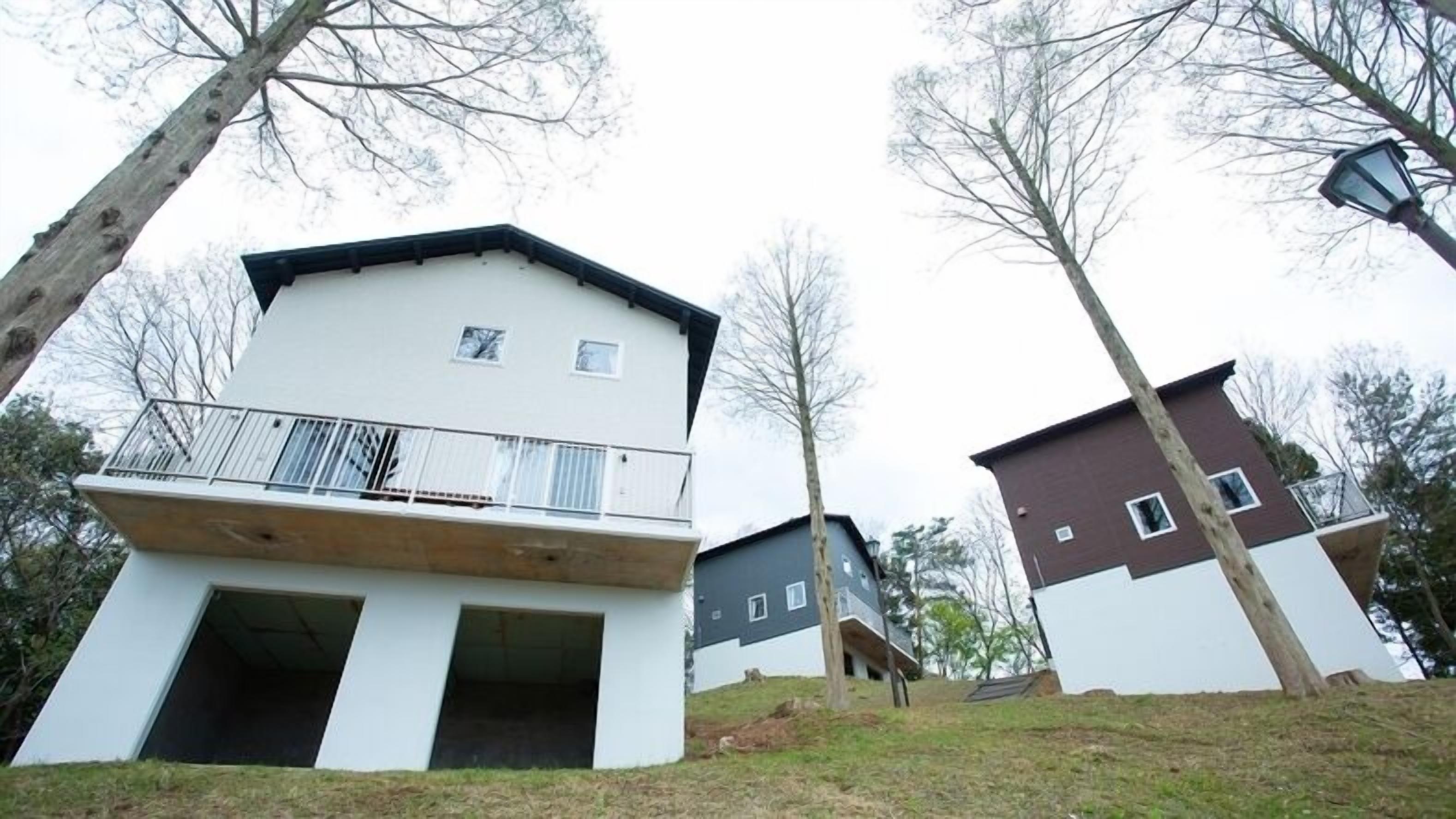 Ein zweistöckiges Wohngebäude mit Balkon, flachem Dach und kleinem Fenster.