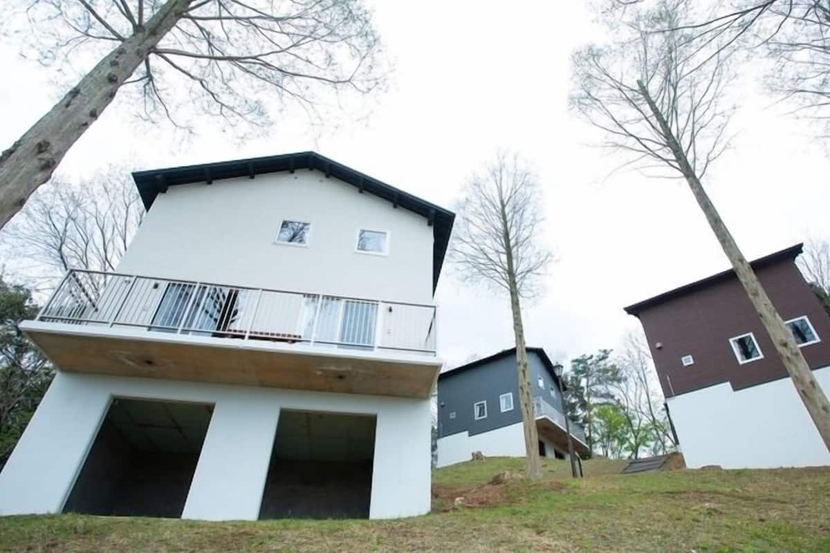 Ein zweistöckiges Wohngebäude mit Balkon, flachem Dach und kleinem Fenster.