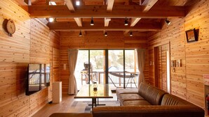L’intérieur d’une cabane avec des murs en bois, un canapé, une table et un téléviseur.
