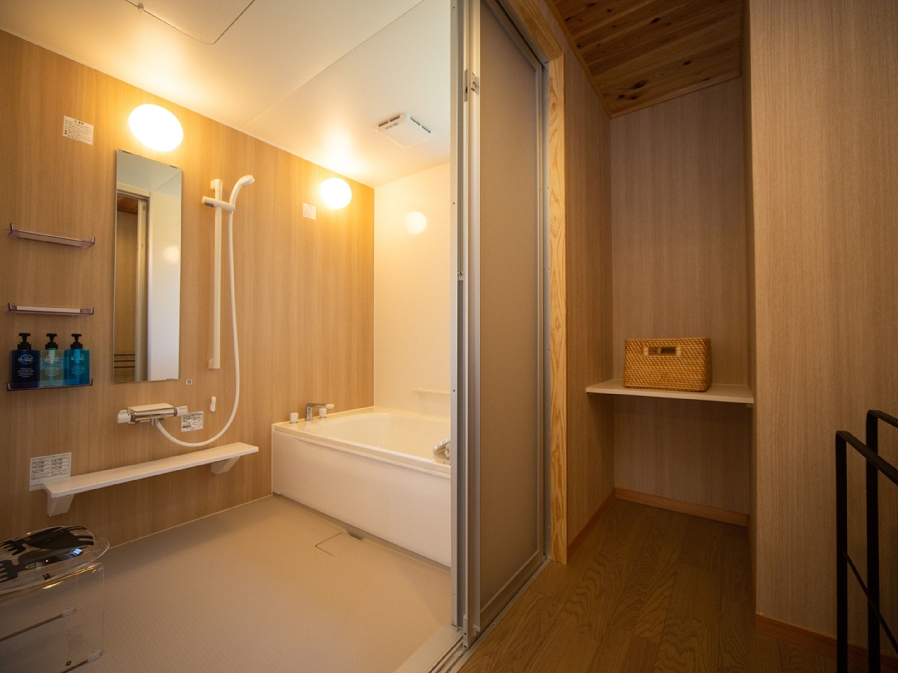 Un baño moderno con tocador de madera, un espejo grande, una bañera y zona de ducha.