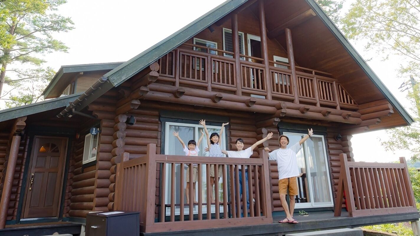Eine Blockhütte mit Balkon, einer Haustür und einem Fenster.