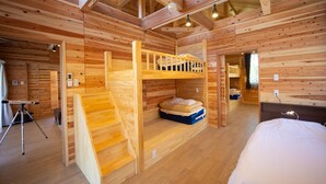 L’intérieur d’un chalet en bois, avec des lits superposés, un escalier et un lit.