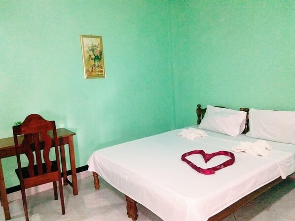 A room with a bed, a chair, and a wall-mounted picture. - Tojo Inn (Puerto Princesa)