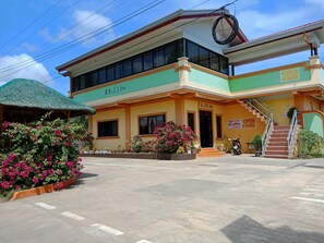 A two-story building with a sign indicating it is a hotel. There is a staircase leading to the entrance, and a motorcycle parked outside. - Tojo Inn (Puerto Princesa)