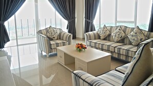 A modern living room with striped sofas and armchairs, a central coffee table with a floral arrangement, and large windows with curtains. - Sri Beverly Hills Near KLIA & KLIA2 & F1 (Nilai)