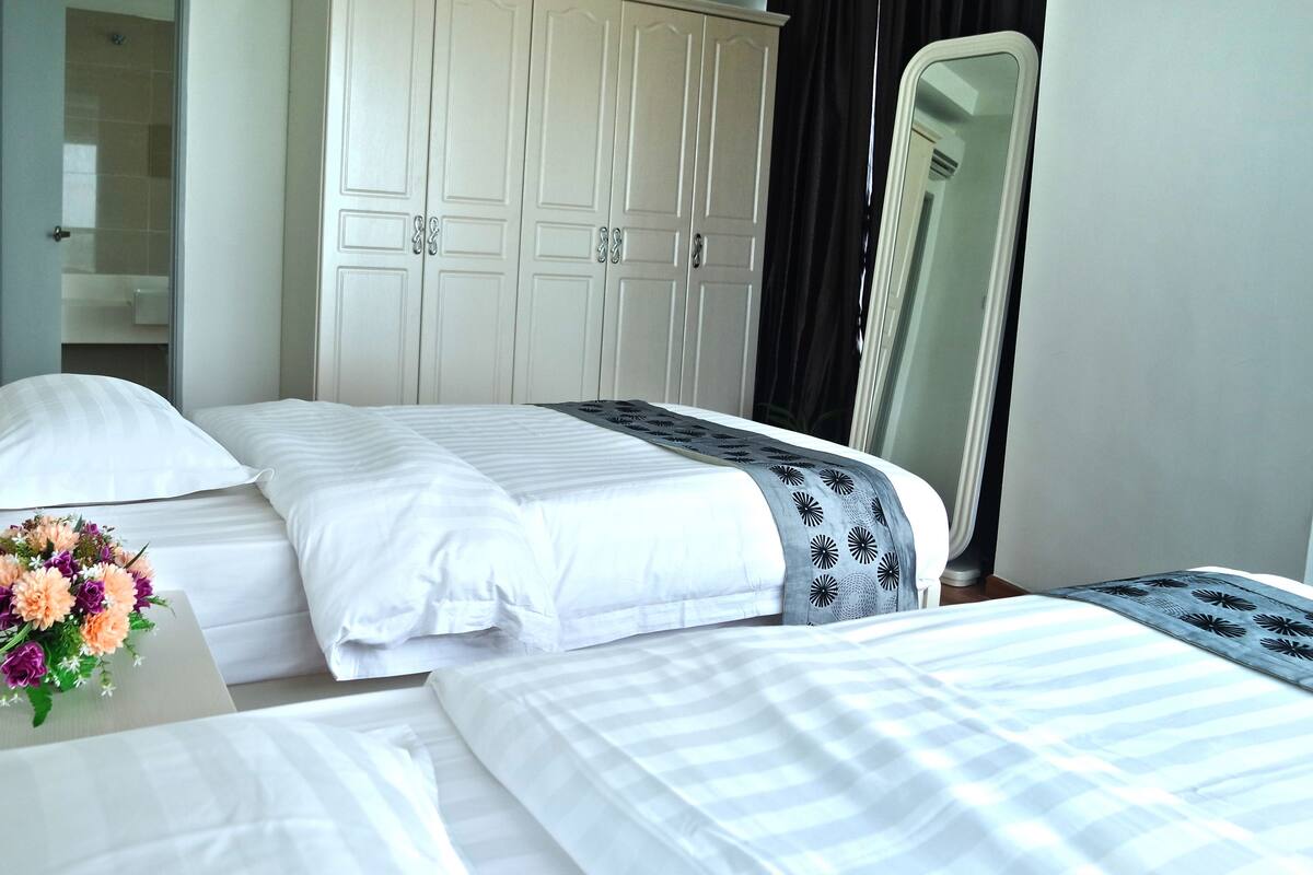 Ein Hotelzimmer mit zwei Betten, einem Spiegel und einem durchgegangenen Tür angedeuteten Badezimmer.